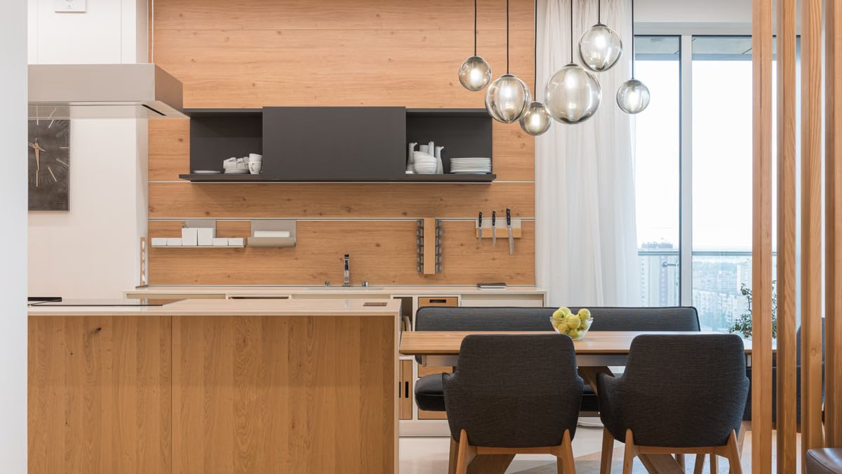 Interior of large modern kitchen with sphere shaped shiny lamps and brown furniture in daytime