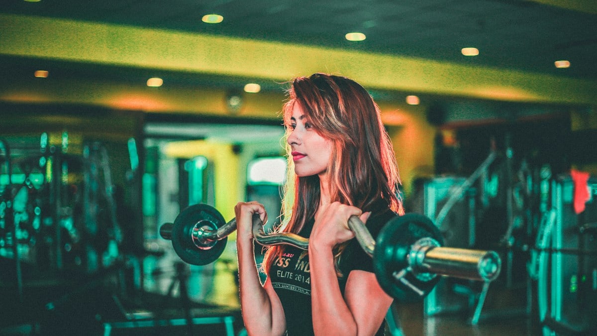 woman lifting black and gray barbell